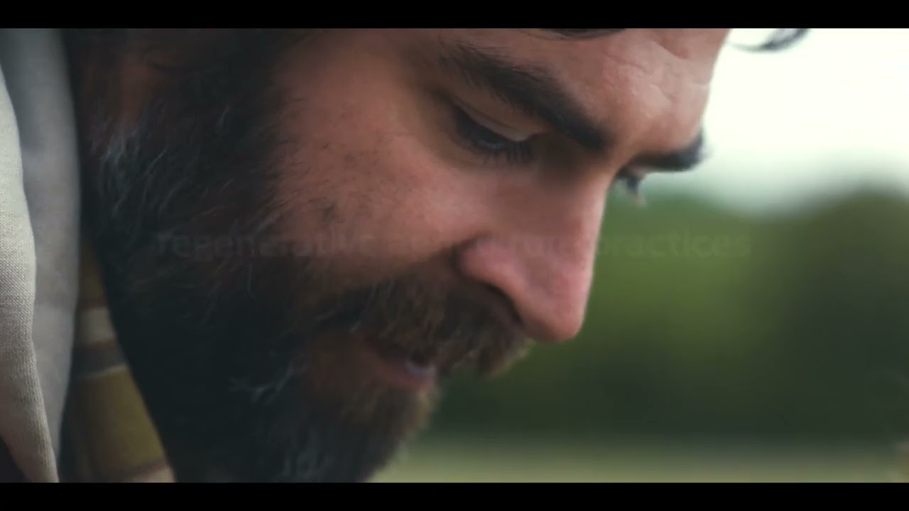 Βίντεο Purina Cares για την Αναγεννητική Γεωργία - Τρεις άνθρωποι περπατούν σε αγροτικό μονοπάτι μέσα σε καλλιεργημένα χωράφια, ενώ ένας σκύλος τρέχει μπροστά τους.